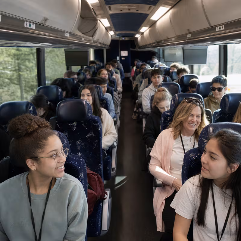 Group boarding a white charter bus for School Transportation transportation in San Diego